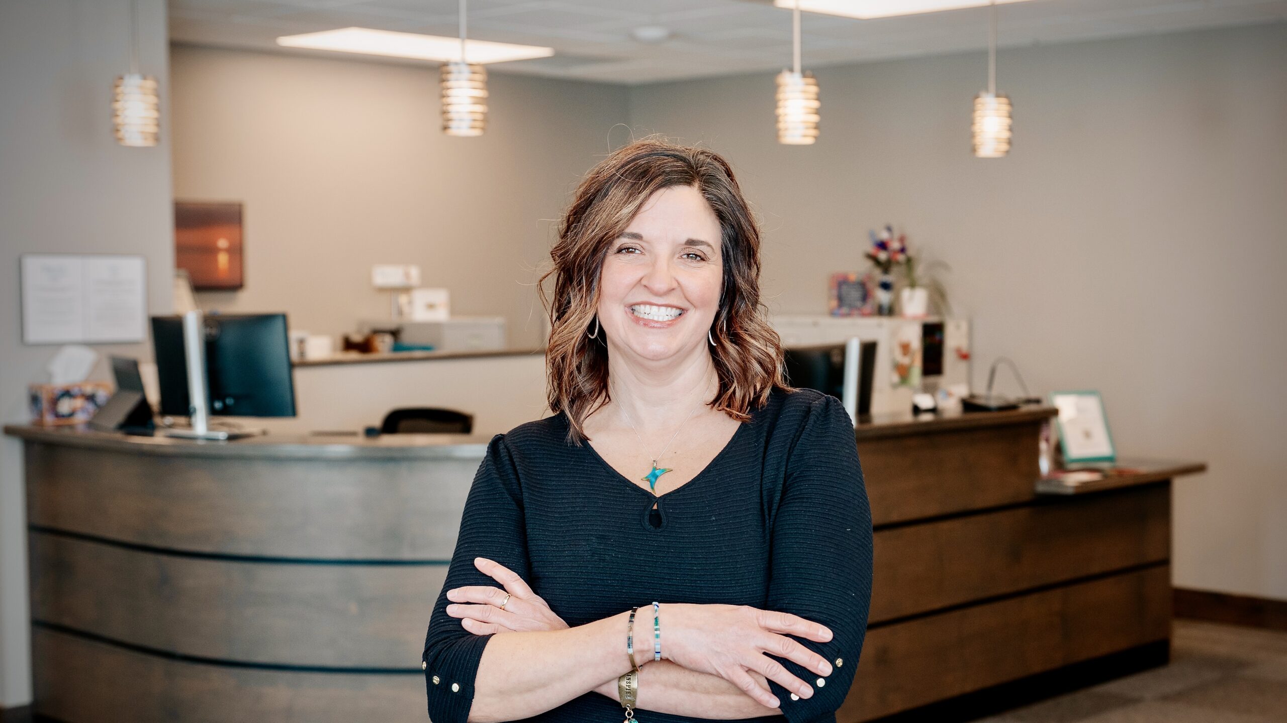 image of a woman standing arms crossed, in front of a business counter