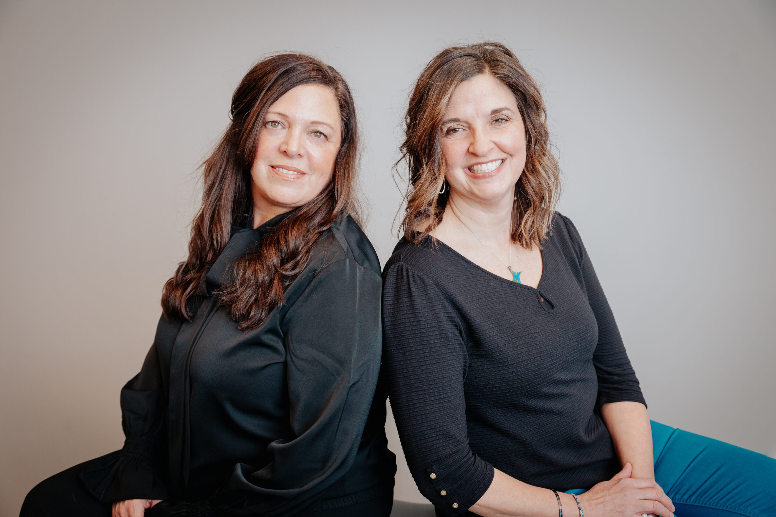 image of two women sitting back to back, facing the camera